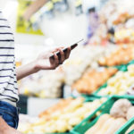 Individual looking at phone in front of produce