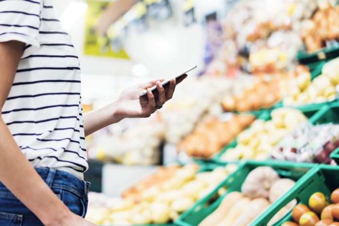 Individual looking at phone in front of produce